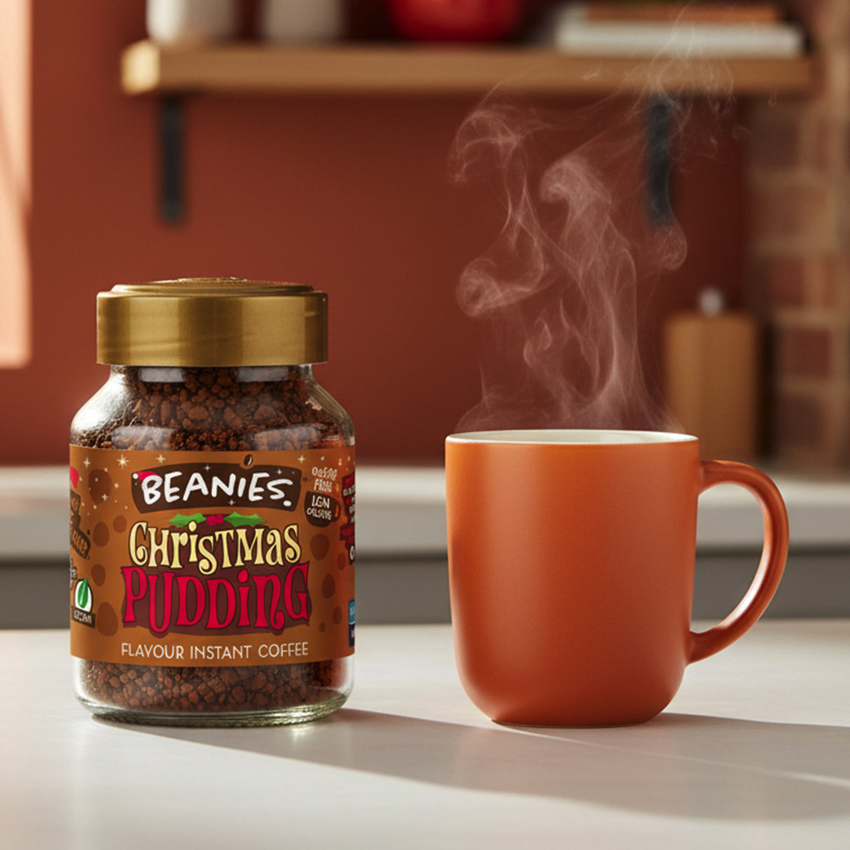 Jar of Beanies Christmas Pudding instant coffee with a steaming orange mug on a kitchen counter.