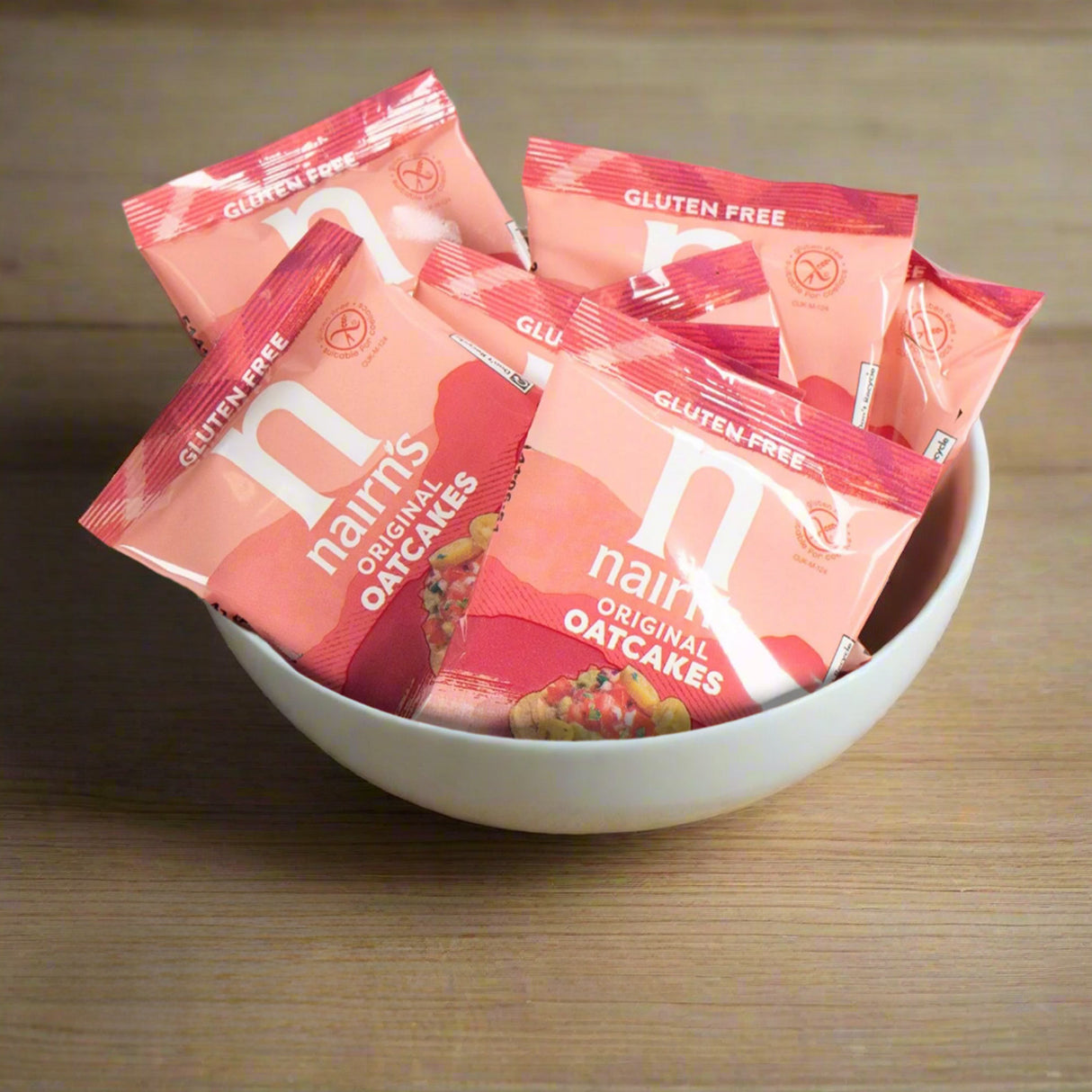 Nairn's gluten-free oatcakes in red packaging in a white bowl on a wooden surface