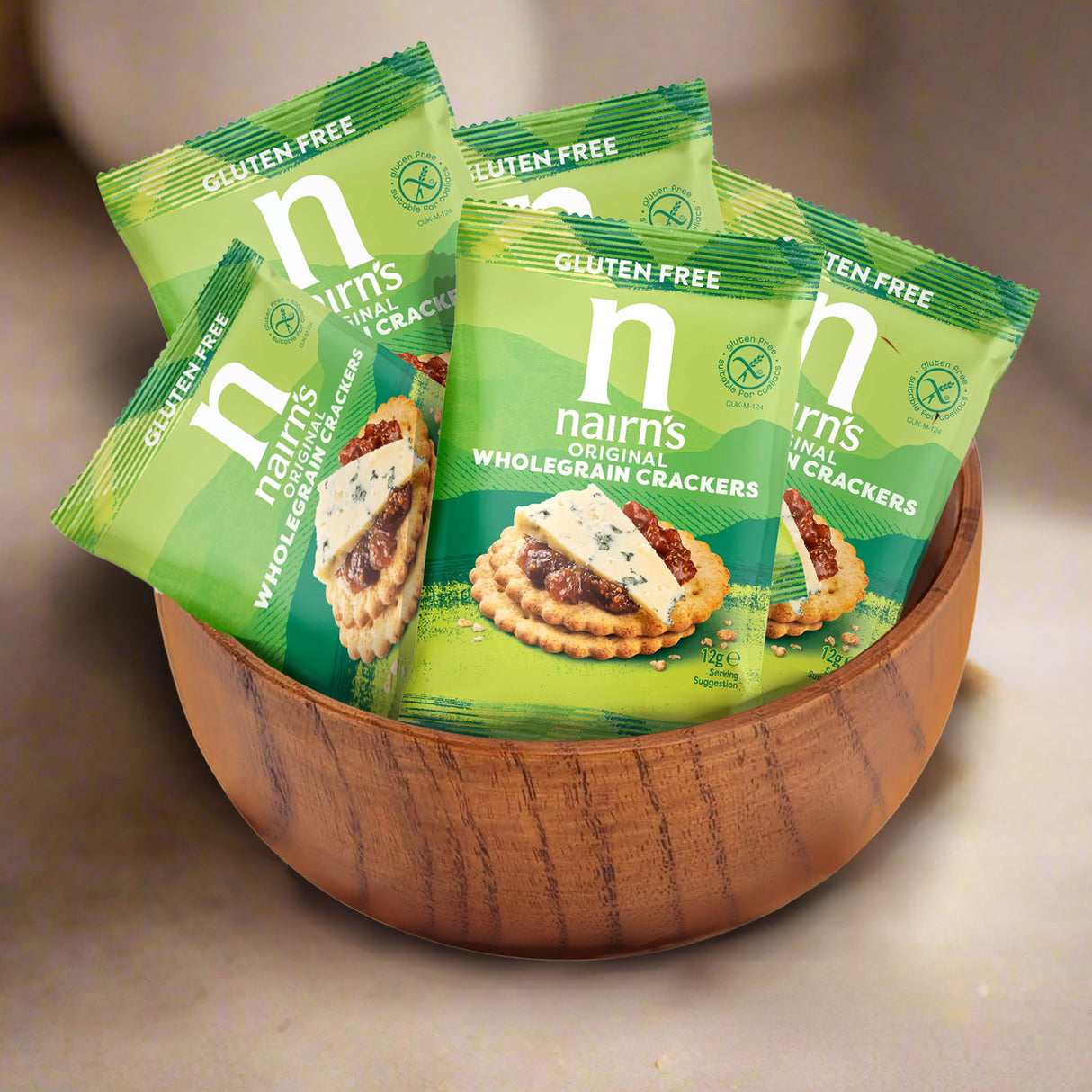 Nairn's wholegrain crackers in green packaging inside a wooden bowl on a neutral background