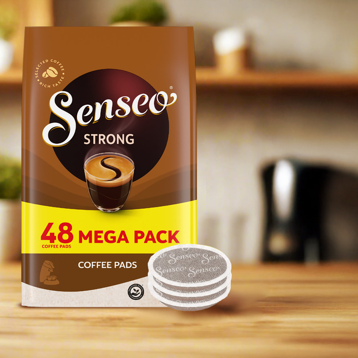 Senseo Strong coffee pads package on a wooden surface with a blurred kitchen background
