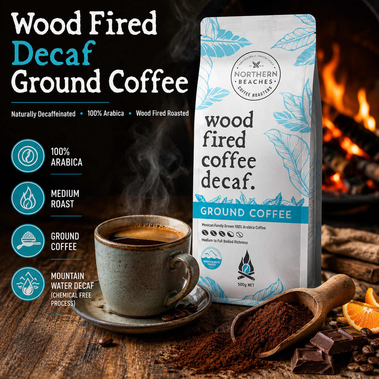 Northern Beaches Wood Fired Decaf Ground Coffee bag shown on a rustic wooden table with a cup of coffee, coffee beans, chocolate, and orange slices, alongside text callouts and a warm fire background.