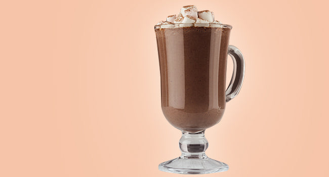 A glass cup of hot chocolate topped with marshmallows cocoa powder 