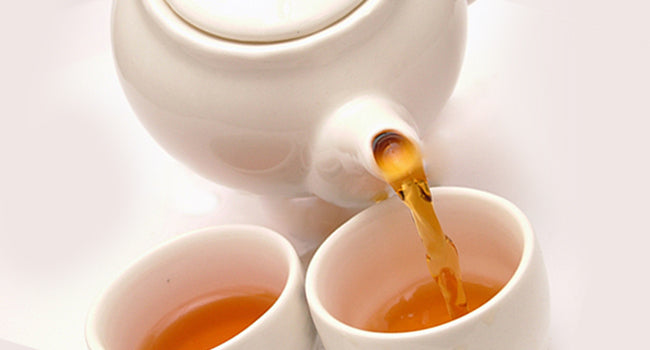 Teapot pouring tea into 2 cups