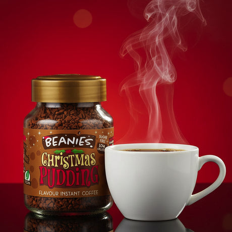 Jar of Beanies Christmas Pudding instant coffee with a steaming white cup on a red background