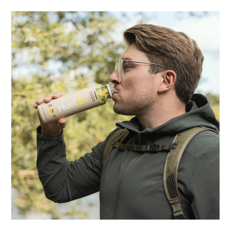 Man drinking from a 'Fueltec' bottle outdoors