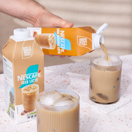 Nescafe Iced Latte being poured into a glass with a hand holding the carton.