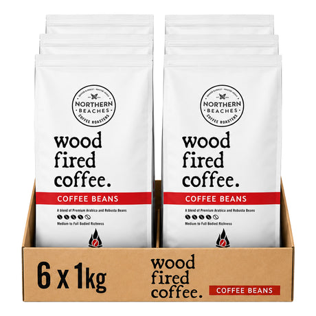 Six bags of Northern Beaches Wood Fired Coffee arranged in a brown cardboard tray, with each bag in a white package featuring black text and a red band labeled 'COFFEE BEANS'.