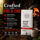 A bag of Northern Beached Coffee 'Wood Fired Coffee' stands next to a ceramic mug in front of a rustic wood stove with an open fire. The left side features promotional text highlighting the coffee's natural woodfire roasting process and flavor profile.