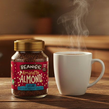 Jar of Beanies Amaretto Almond instant coffee next to a steaming white mug on a wooden surface.