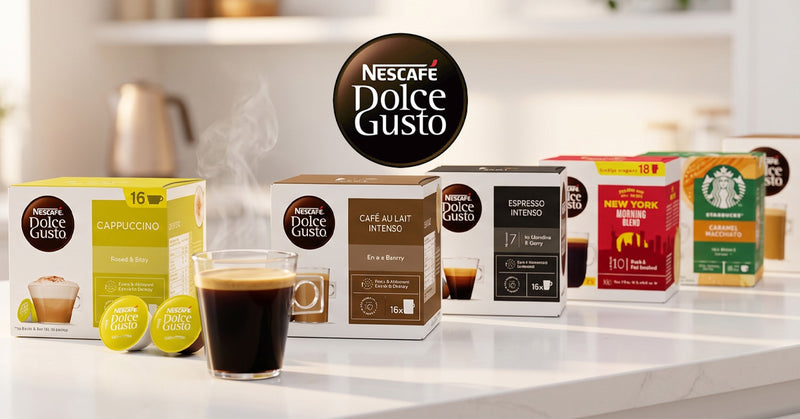 A countertop display of Nescafé Dolce Gusto coffee capsule boxes in multiple flavors, alongside several yellow single-serve capsules and a glass of black coffee with foam, set against a softly blurred kitchen background.