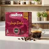 Lavazza Lungo Dolce coffee box in a kitchen setting next to a cup of espresso with coffee beans scattered in front.