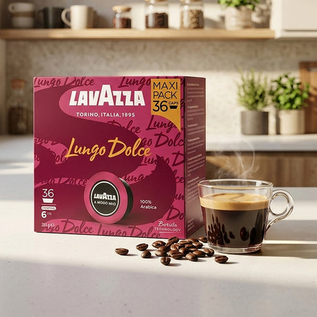 Lavazza Lungo Dolce coffee box in a kitchen setting next to a cup of espresso with coffee beans scattered in front.