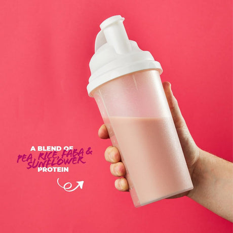 A hand holding a frosted translucent protein shaker bottle filled with a pale pink drink against a solid pink background, with text on the left reading 'A BLEND OF PEA, RICE, FLEA & SUNFLOWER PROTEIN'.
