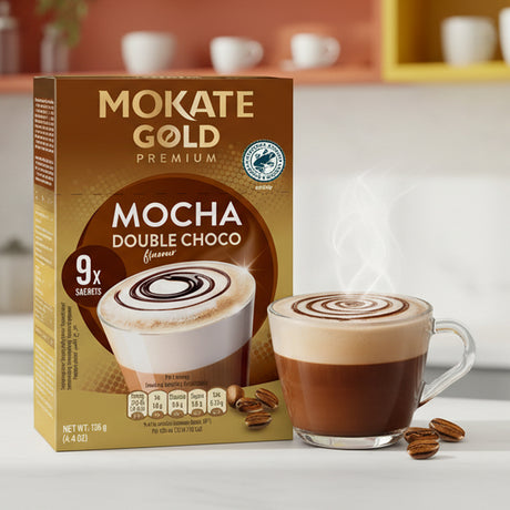Mokate Gold Mocha Double Choco coffee packaging with a cup of coffee on a blurred kitchen background