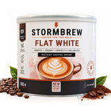 A 1kg canister of Stormbrew Flat White instant coffee drink, surrounded by scattered coffee beans and ground coffee on a white background.