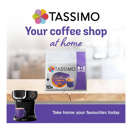 Tassimo coffee machine and Tassimo Cadbury chocolate coffee pack on a wooden surface with a blurred background.