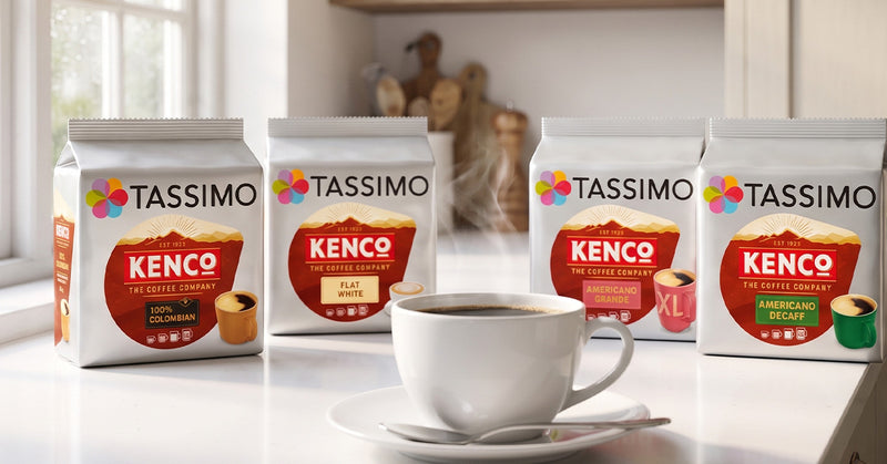 Four bags of Tassimo Kenco coffee pods arranged on a white countertop beside a white cup and saucer in a bright kitchen setting.