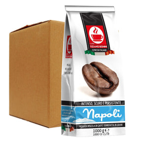 A 1000g bag of Napoli espresso coffee stands in front of a plain brown cardboard shipping box on a white background. The bag is white with a prominent red and black Napoli logo, a photo of roasted coffee beans, and blue brand lettering near the bottom.