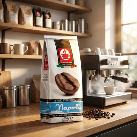 A 1000g bag of Napoli Intenso Scuro coffee stands on a wooden countertop in a warm, sunlit kitchen or cafe setting, with an espresso machine, coffee beans, and wooden shelves in the background.