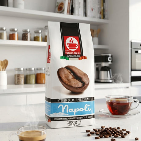 A bag of Napoli espresso coffee stands on a kitchen counter with a cup of espresso, loose coffee beans, and a glass cup of tea in a bright, modern kitchen setting.
