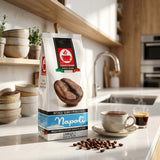 A bag of Espresso Roma Napoli coffee beans stands on a kitchen counter beside a cup of coffee, a glass of espresso, scattered coffee beans, and stacked ceramic bowls, with a blurred kitchen background.